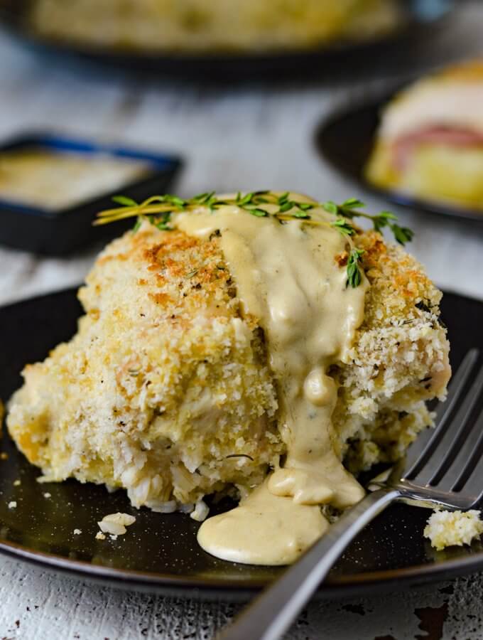 Baked Chicken Cordon Bleu with a creamy mustard sauce and a couple sprigs of thyme sitting on top.