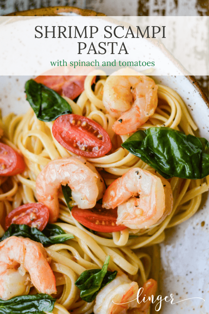 A bowl of shrimp scampi pasta with spinach and tomatoes.