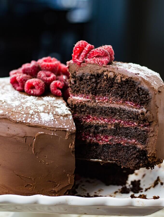 A layered chocolate raspberry cake with a piece being pulled away from it.